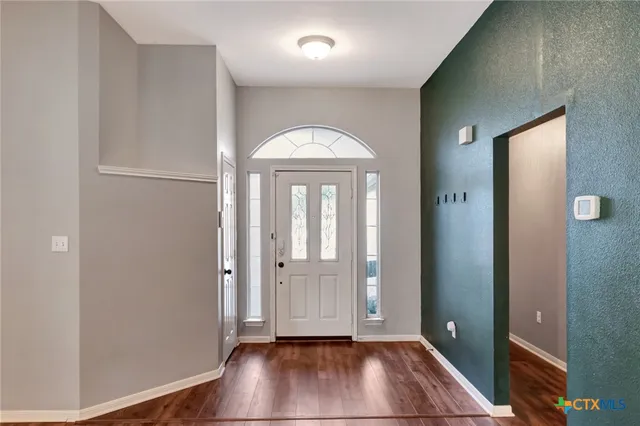 an empty room with wooden floor and a ceiling fan
