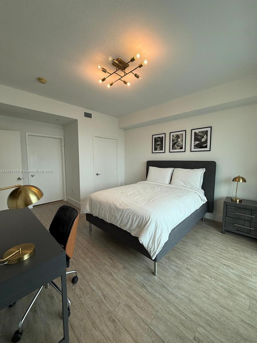 1111 Southwest 1st Avenue, Unit UPH4017 Miami, FL 33130 - Photo 7 of 14 a bedroom with a bed and a chandelier