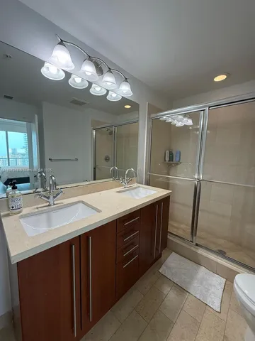 a bathroom with a granite countertop sink a large mirror and a shower
