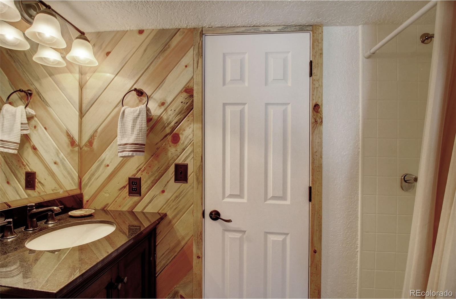 4345 Evans Road Monument, CO 80132 - Photo 37 of 40 a bathroom with a granite countertop sink a mirror a vanity and a shower