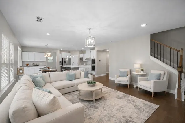 a kitchen with stainless steel appliances kitchen island granite countertop a refrigerator a stove a sink a dining table and chairs with wooden floor