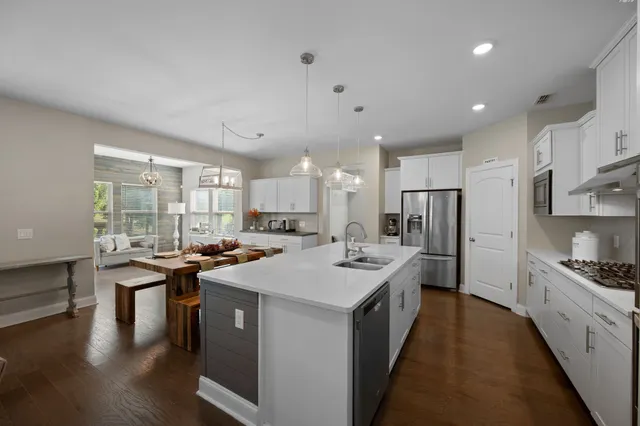 a kitchen with stainless steel appliances kitchen island granite countertop a stove top oven a sink dishwasher a dining table and chairs with wooden floor