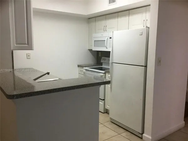 a white refrigerator freezer and a stove sitting inside of a kitchen