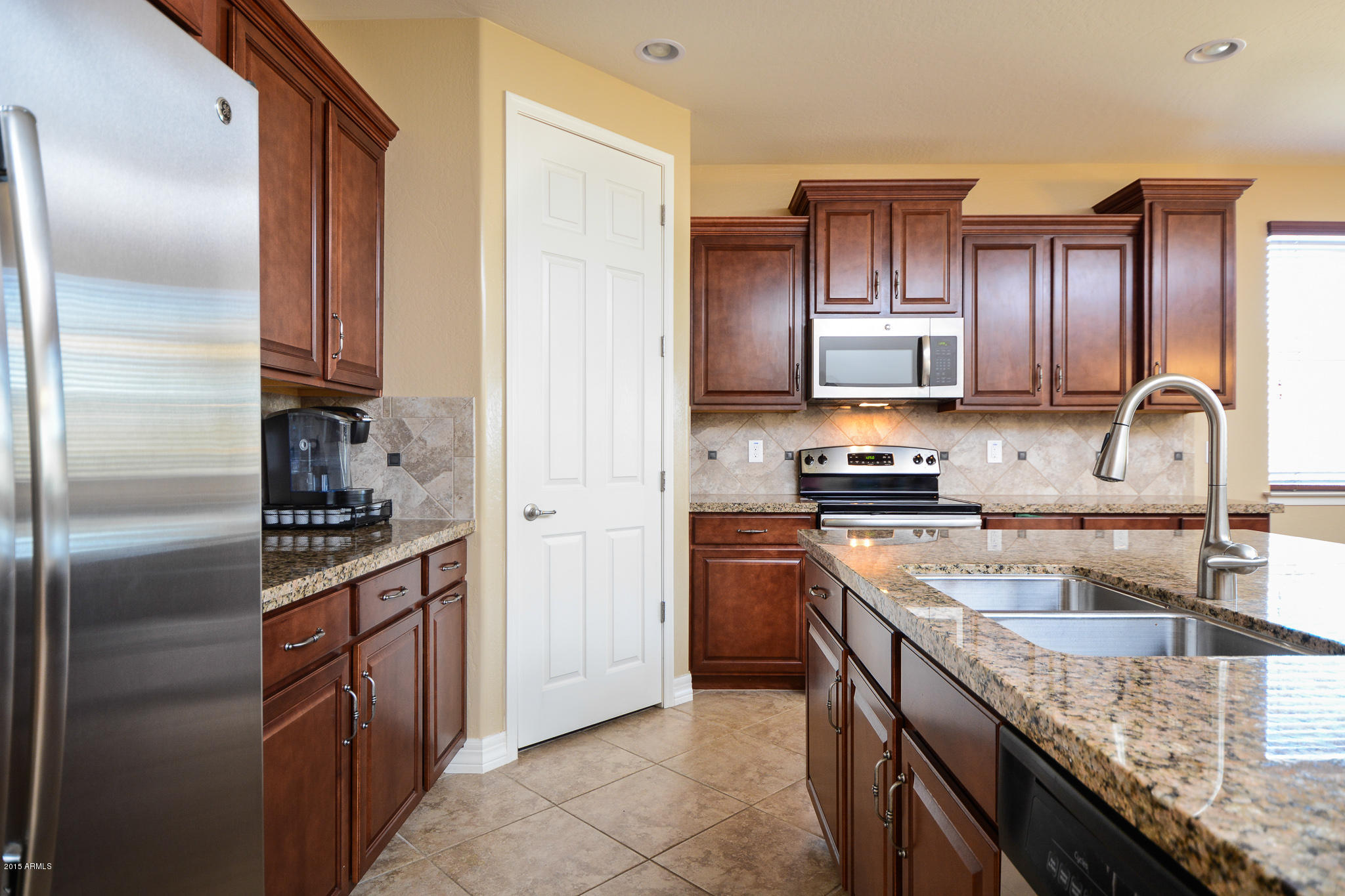 7545 West Redbird Road Peoria, AZ 85383 - Photo 3 of 23 a kitchen with kitchen island granite countertop a sink stainless steel appliances and cabinets