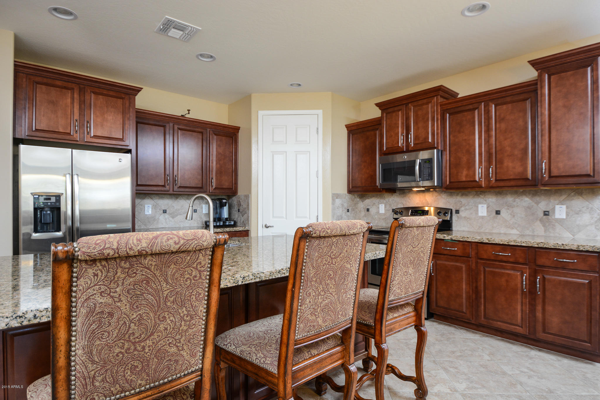 7545 West Redbird Road Peoria, AZ 85383 - Photo 4 of 23 a kitchen with stainless steel appliances granite countertop a stove a refrigerator a sink dishwasher and wooden cabinets