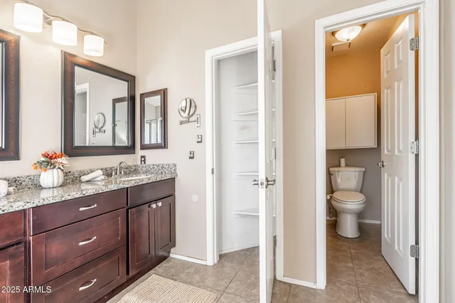 a bathroom with a granite countertop toilet a sink and a mirror