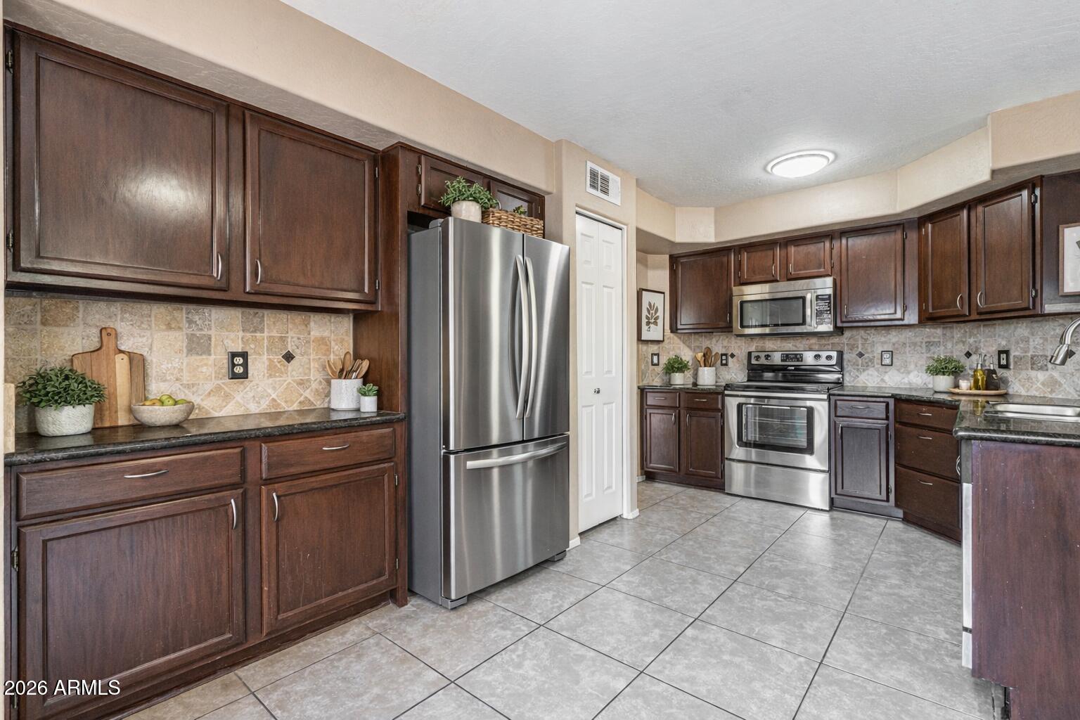 15601 South 37th Way Phoenix, AZ 85048 - Photo 9 of 38 a kitchen with granite countertop stainless steel appliances and wooden cabinets