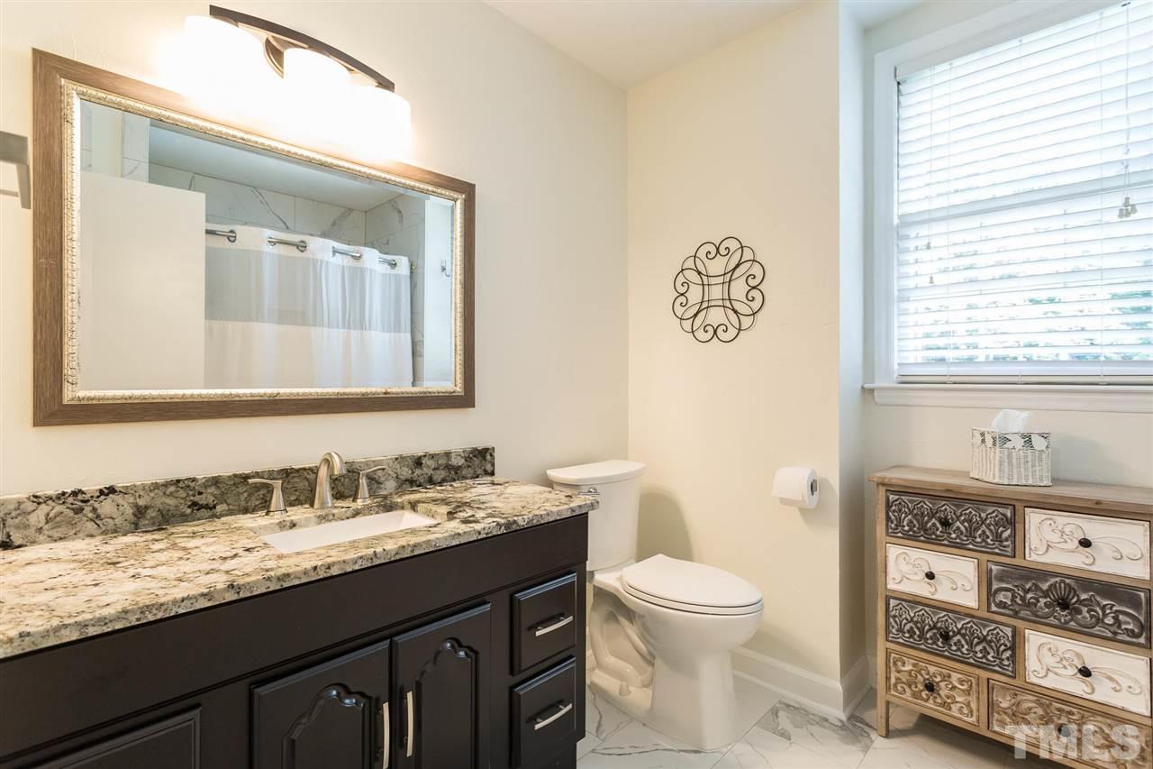 4300 Pike Road Raleigh, NC 27613 - Photo 24 of 28 a bathroom with a granite countertop toilet a sink and a mirror
