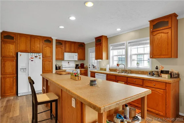 a kitchen with a refrigerator a sink dishwasher a stove and a dining table with wooden cabinet