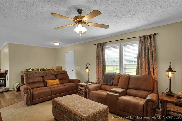 a living room with furniture a ceiling fan and a large window