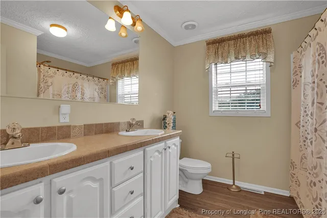 a bathroom with a granite countertop sink a large mirror a toilet and a window