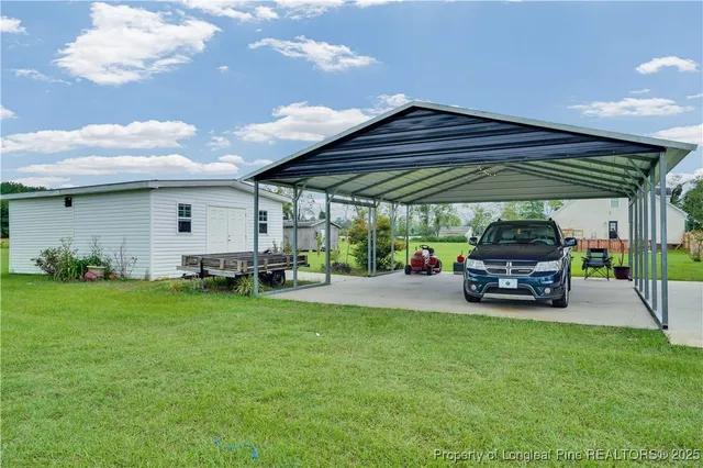 a view of a backyard with table and chairs under an umbrella with a fire pit