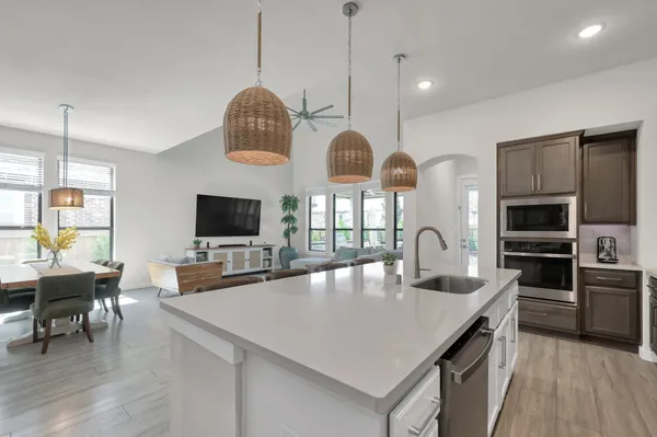 a kitchen with stainless steel appliances a stove a sink a microwave a dining table and chairs