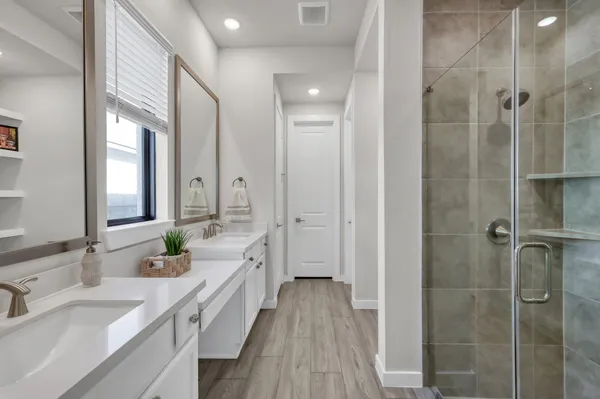 a spacious bathroom with a double vanity sink a mirror and a shower