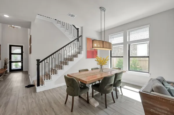 a dining room with wooden floor a chandelier a wooden table and chairs