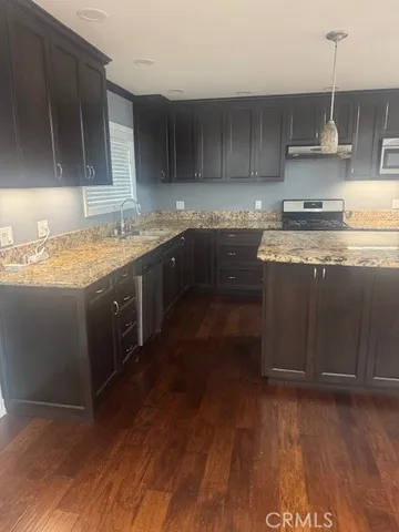 a kitchen with granite countertop a stove a sink and a wooden cabinets