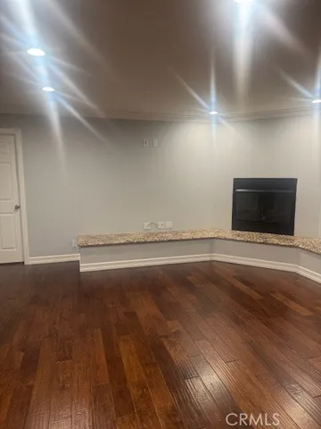 a view of an empty room with wooden floor and a fireplace