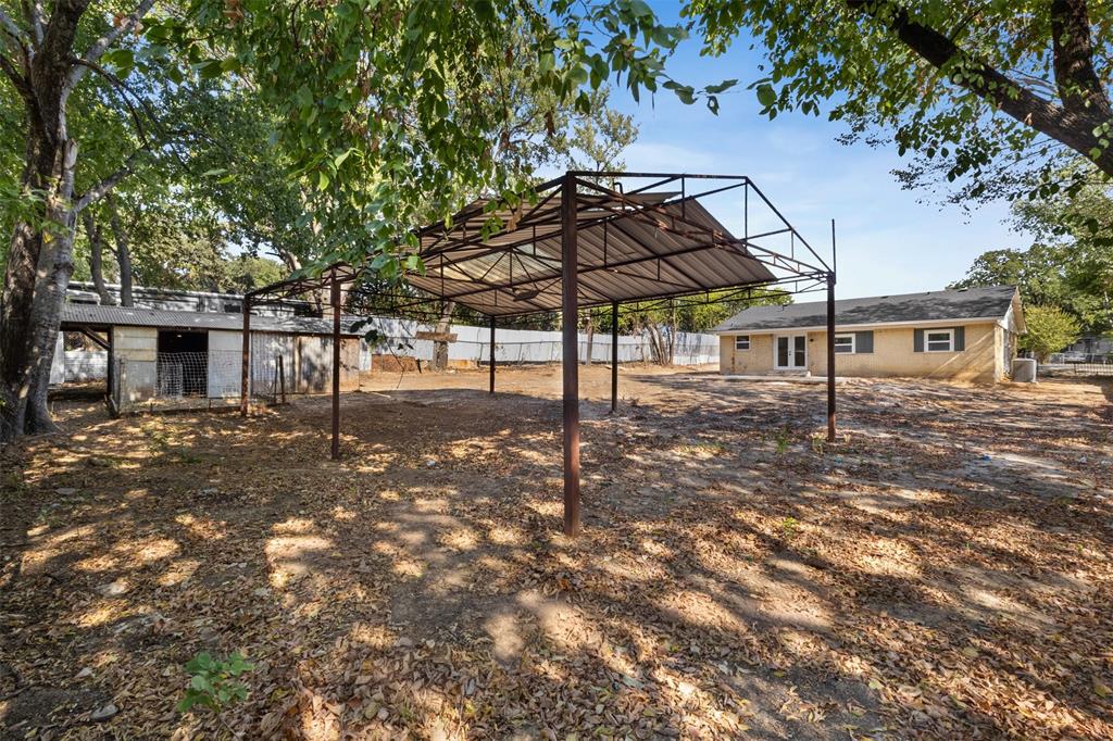 1903 Beauford Road Dallas, TX 75253 - Photo 24 of 27 Expansive outdoor space featuring a covered metal structure, additional outbuilding, and mature trees