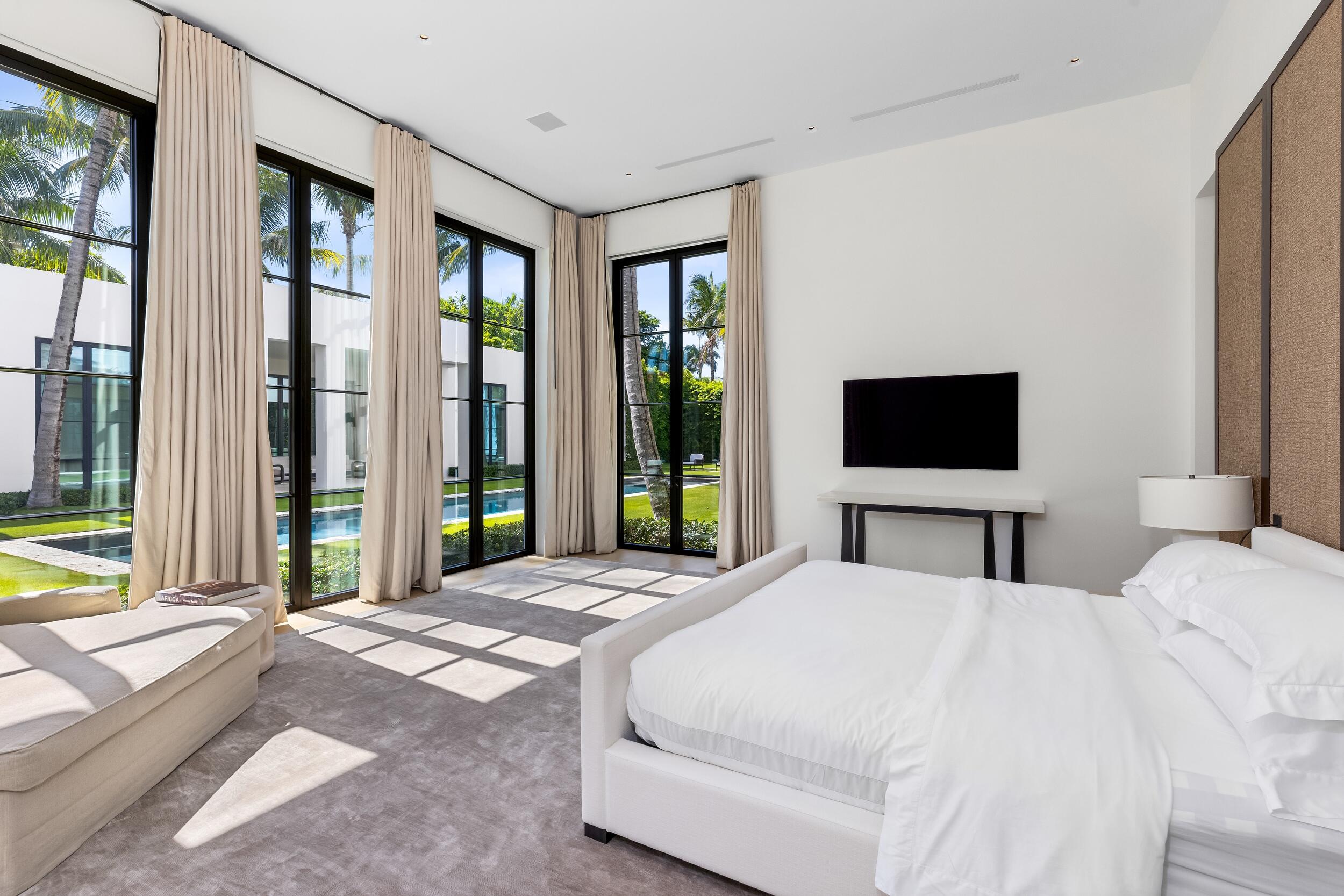 241 Jungle Road Palm Beach, FL 33480 - Photo 47 of 96 a bedroom with a large bed and a flat tv screen next to a window