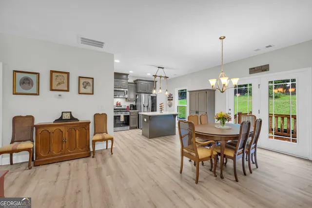 a dining room with furniture a chandelier and wooden floor