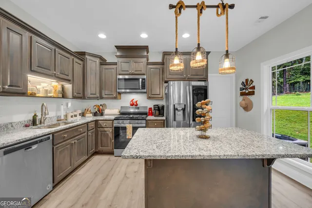 a kitchen with stainless steel appliances granite countertop a sink a stove and a wooden floors