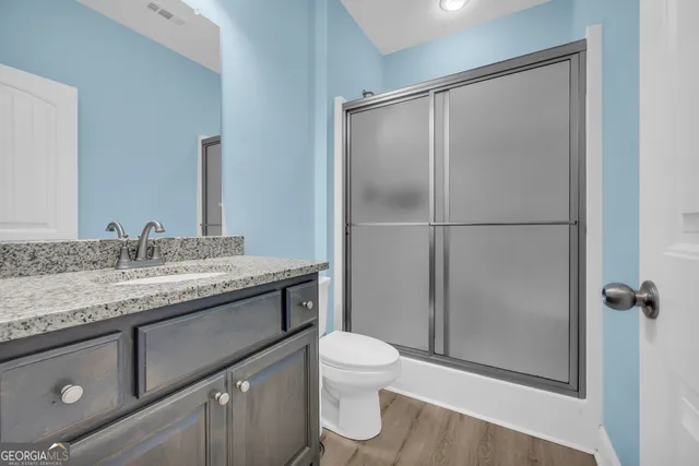 a bathroom with a granite countertop sink toilet and shower
