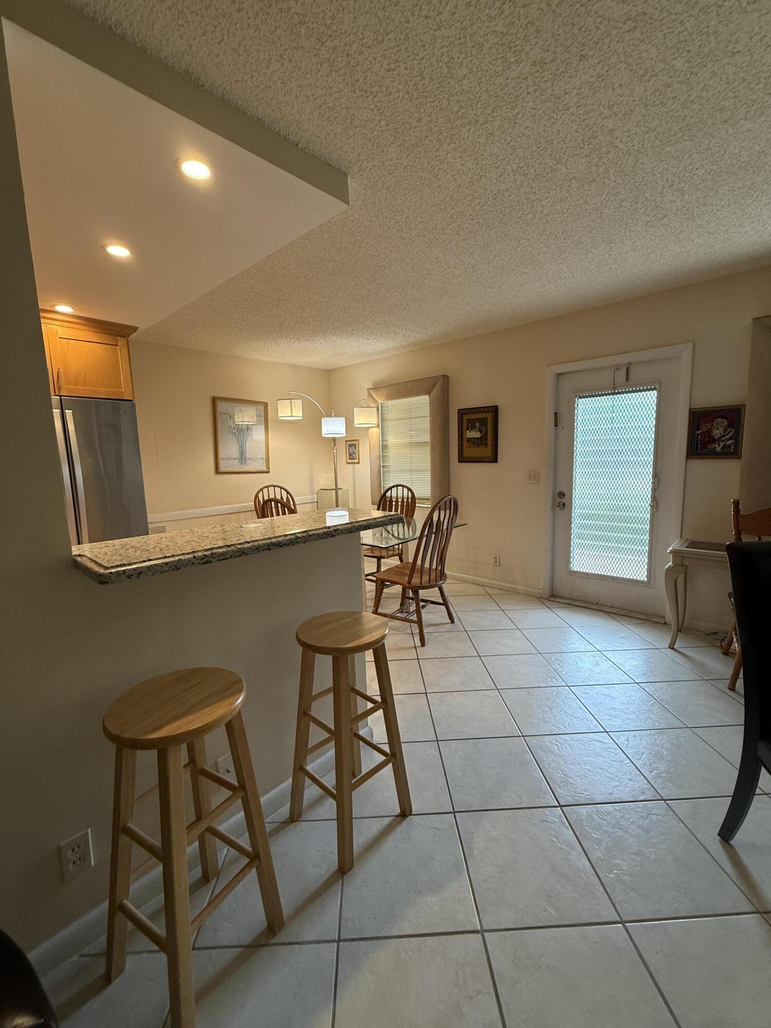 1046 Wolverton C Boca Raton, FL 33434 - Photo 3 of 17 a dining hall with a stove a sink a dining table and chairs