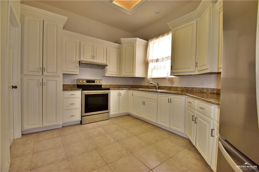1104 Rio Balsas Mission, TX 78572 - Photo 3 of 20 Kitchen featuring stainless steel appliances, dark stone counters, under cabinet range hood, and light tile patterned flooring