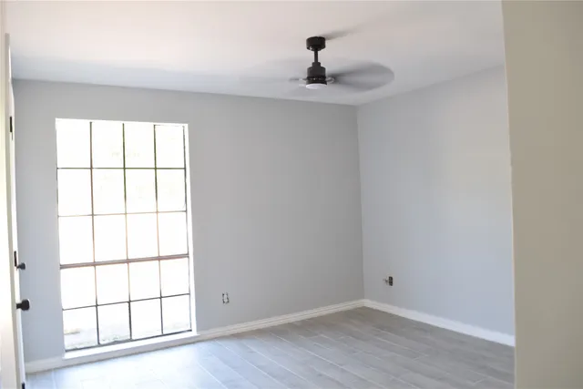 a view of an empty room with a window and wooden floor