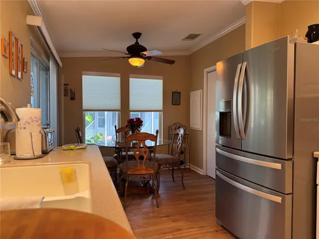 a kitchen with stainless steel appliances granite countertop a refrigerator a stove and a dining table with wooden floor