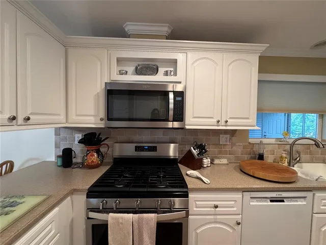 a large kitchen with stainless steel appliances granite countertop a stove a sink dishwasher and a microwave with wooden floor