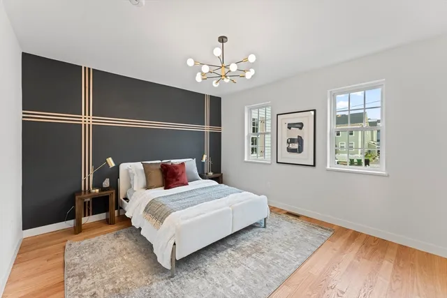 a bedroom with a large bed chandelier and a window