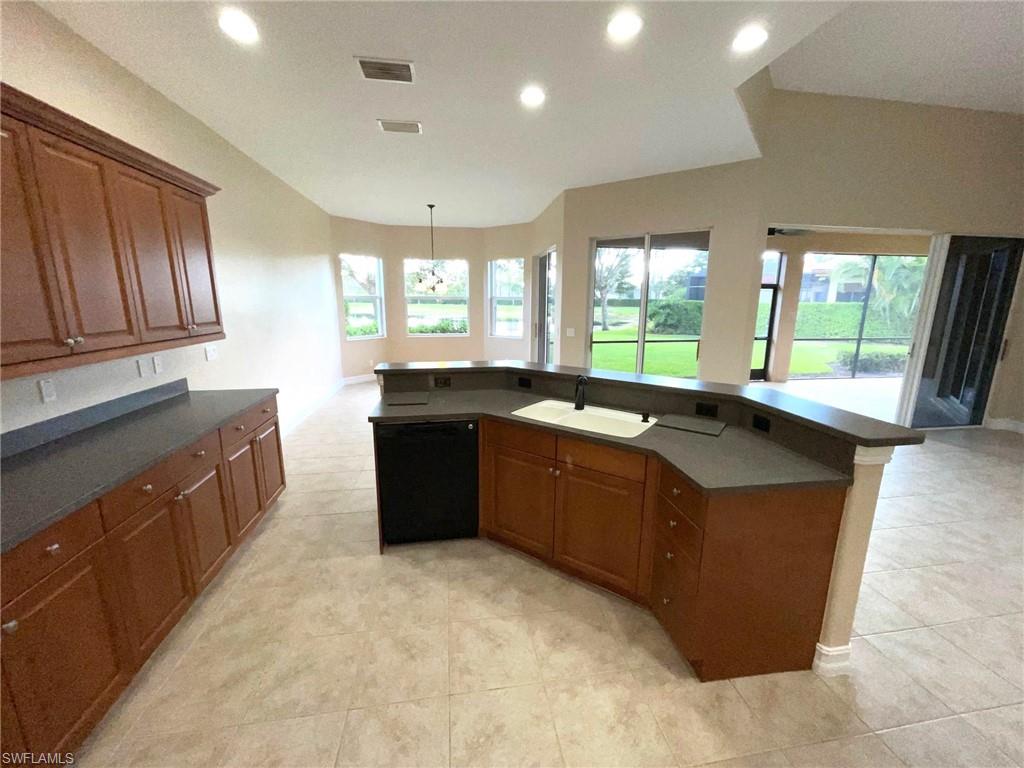 6082 Divot Court Naples, FL 34113 - Photo 15 of 39 a large kitchen with kitchen island granite countertop a sink a counter top space and stainless steel appliances
