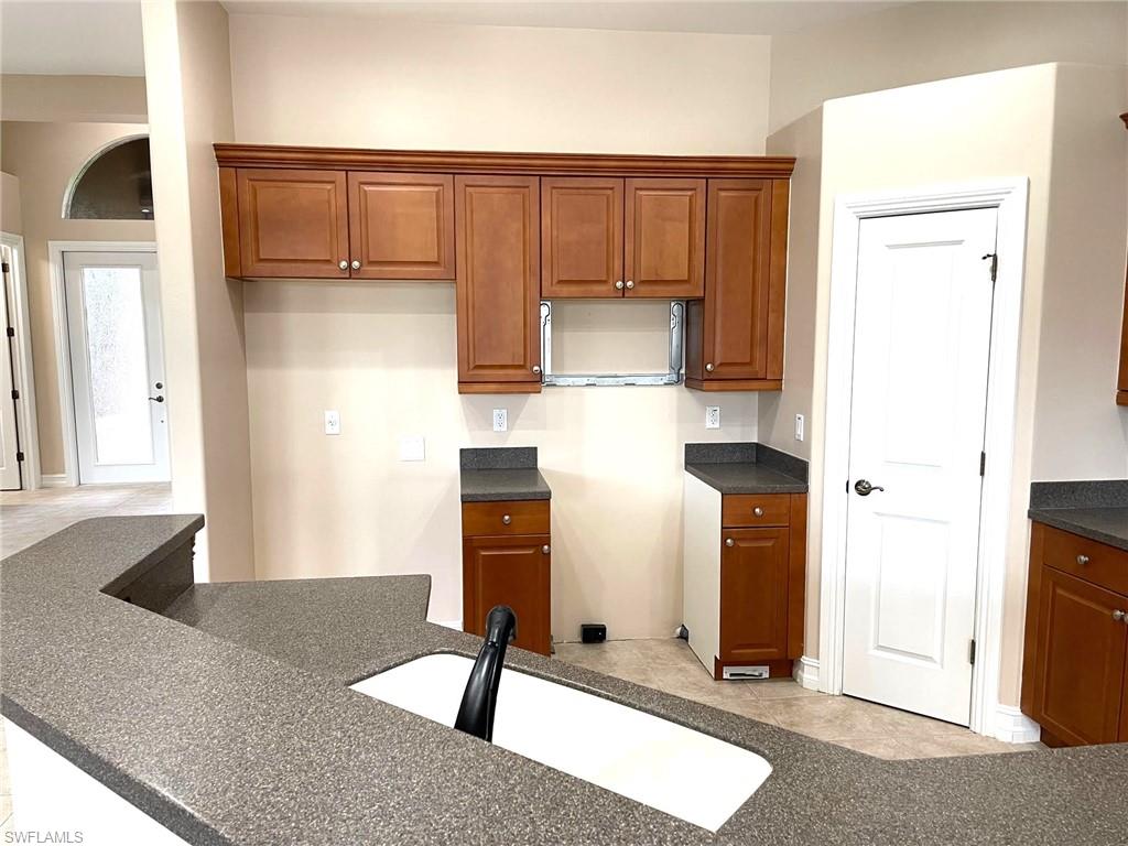 6082 Divot Court Naples, FL 34113 - Photo 18 of 39 a kitchen with a refrigerator and a sink