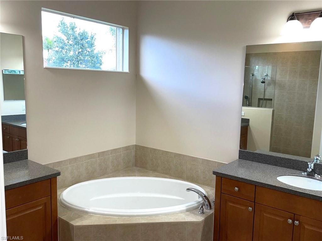 6082 Divot Court Naples, FL 34113 - Photo 23 of 39 a bathroom with a granite countertop sink a toilet a mirror and window