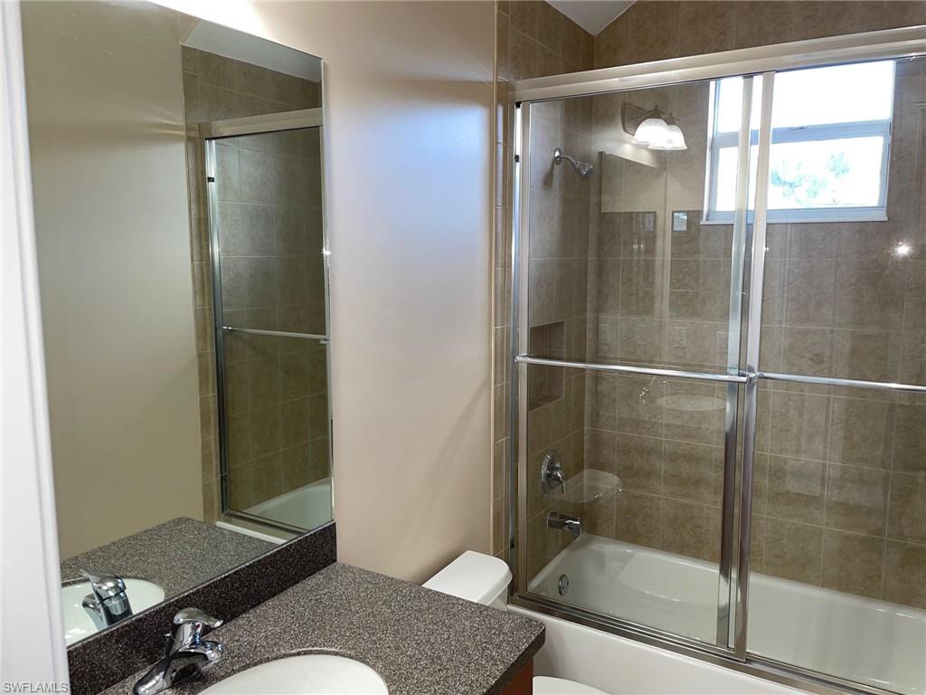 6082 Divot Court Naples, FL 34113 - Photo 31 of 39 a bathroom with a granite countertop shower mirror and a sink