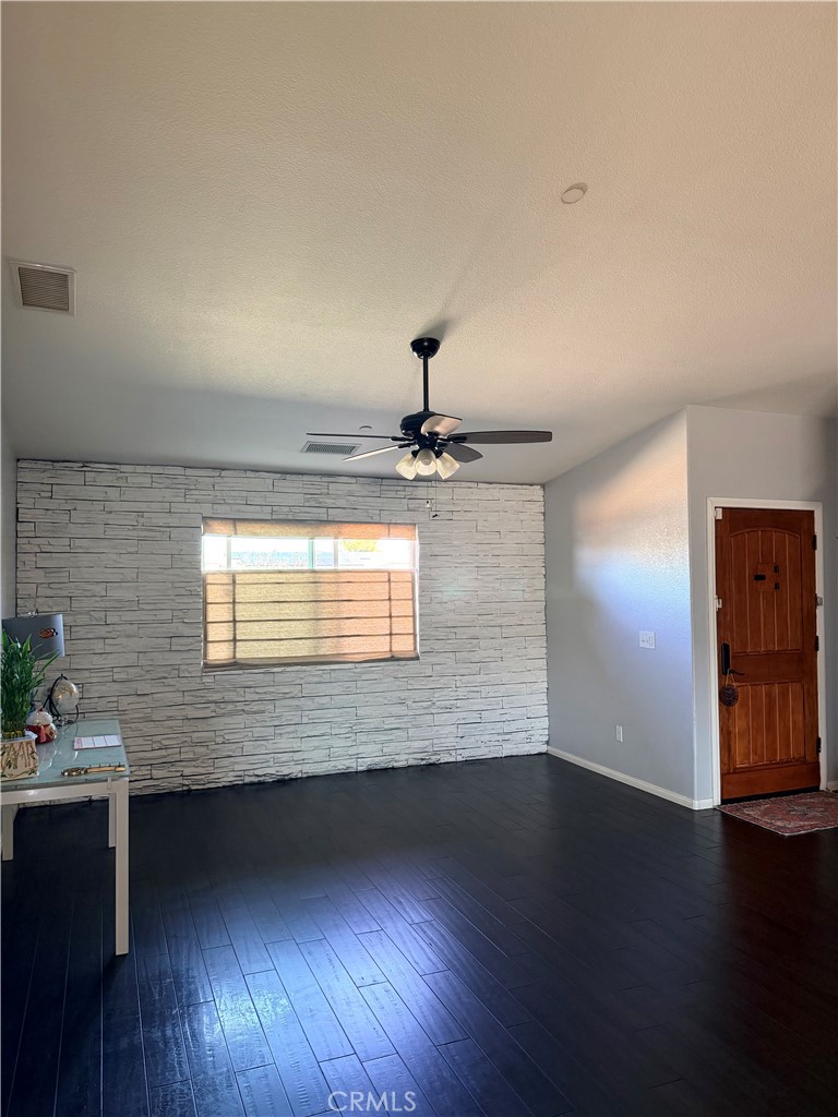 12833 Algonquin Road Apple Valley, CA 92308 - Photo 10 of 16 a view of an empty room with wooden floor and a window