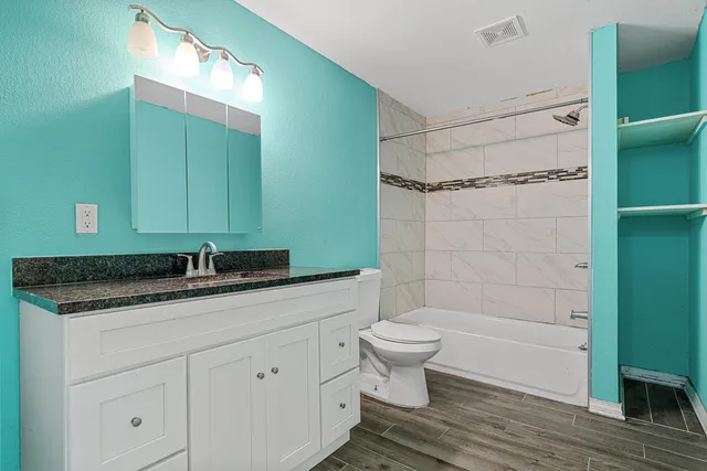 a bathroom with a granite countertop sink toilet a mirror and shower