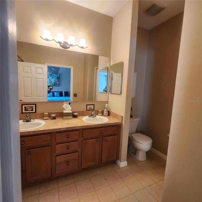 14982 Skip Jack Loop Lakewood Ranch, FL 34202 - Photo 15 of 28 a bathroom with a double vanity sink a toilet and a mirror