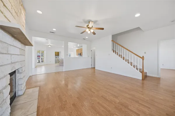 a view of an empty room with wooden floor and a ceiling fan