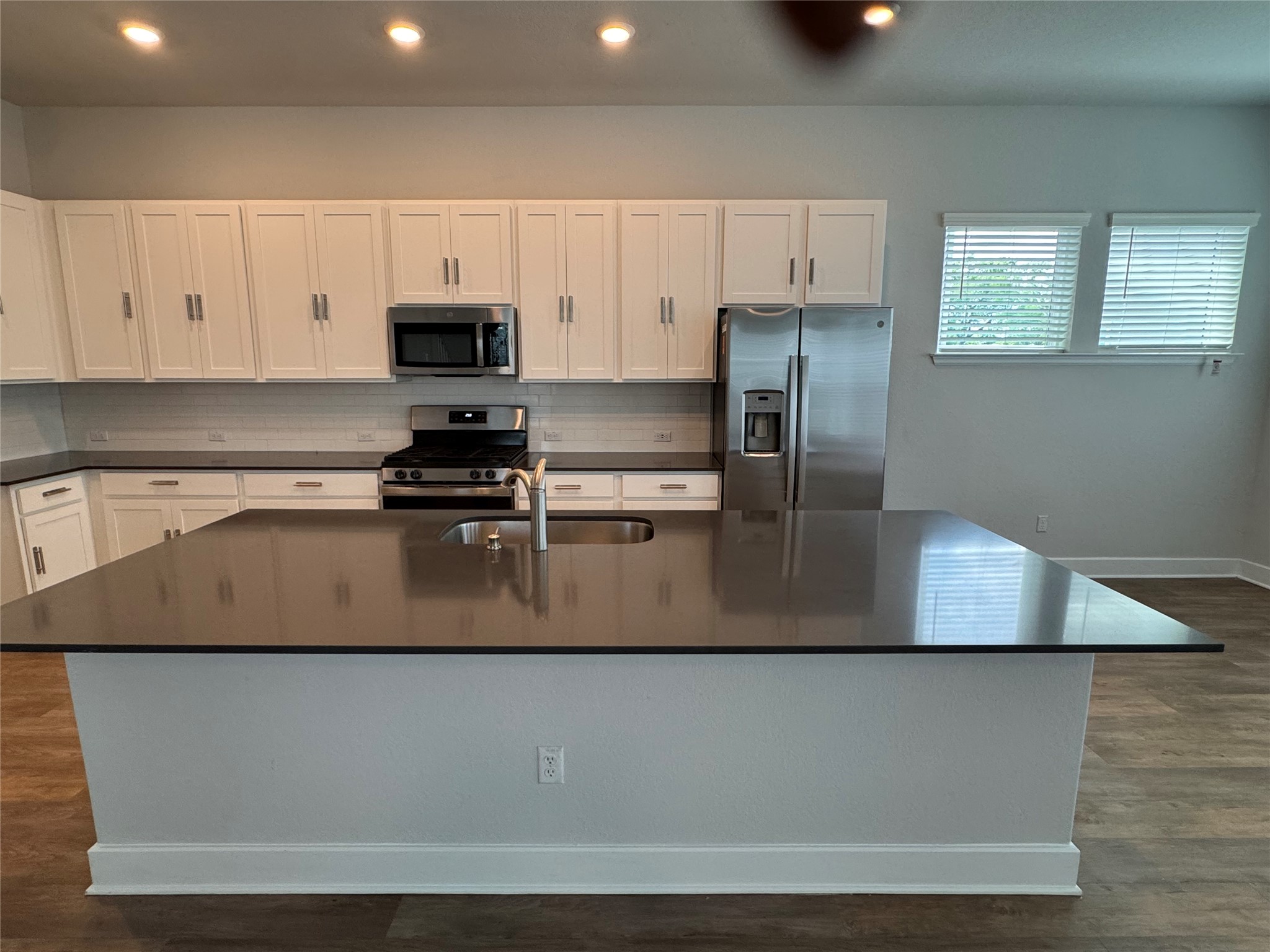 3000 Chisholm Trail Road, Unit 33 Round Rock, TX 78681 - Photo 5 of 31 a kitchen with kitchen island a sink a stove a refrigerator and white cabinets