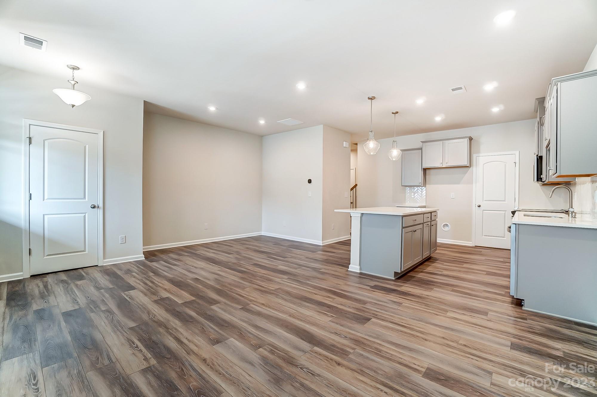 15317 Braid Mdw Drive, Unit 170 Charlotte, NC 28278 - Photo 28 of 29 a large white kitchen with kitchen island a sink wooden floor and a refrigerator