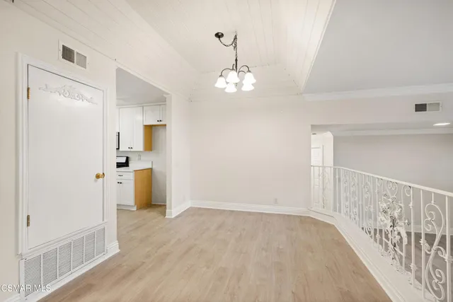 a view of a hallway with wooden floor and a kitchen