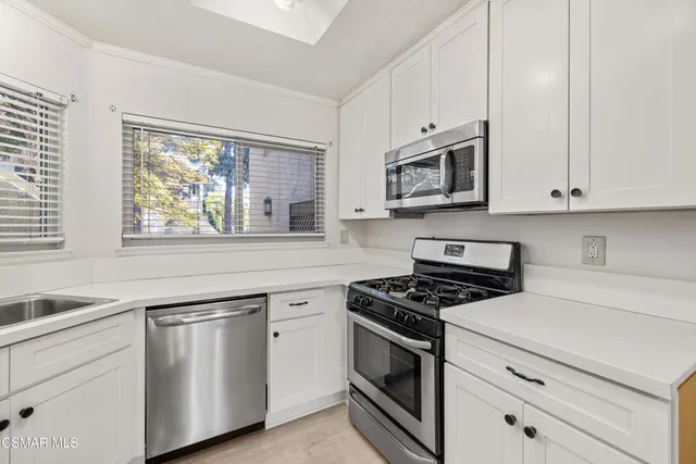a kitchen with white cabinets stainless steel appliances and a window