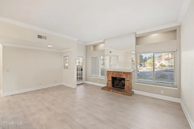an empty room with fireplace wooden floor and windows