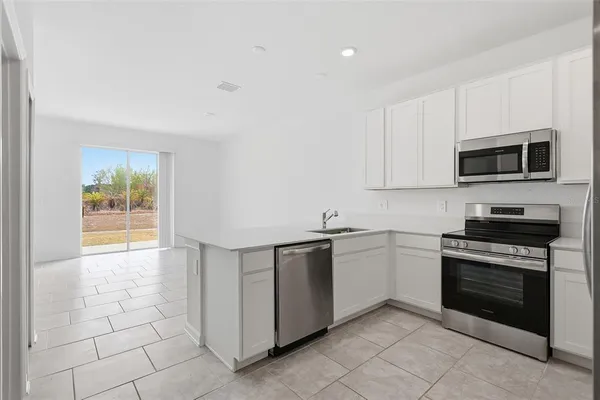 a kitchen with stainless steel appliances granite countertop a stove top oven a sink dishwasher and a refrigerator with wooden cabinets