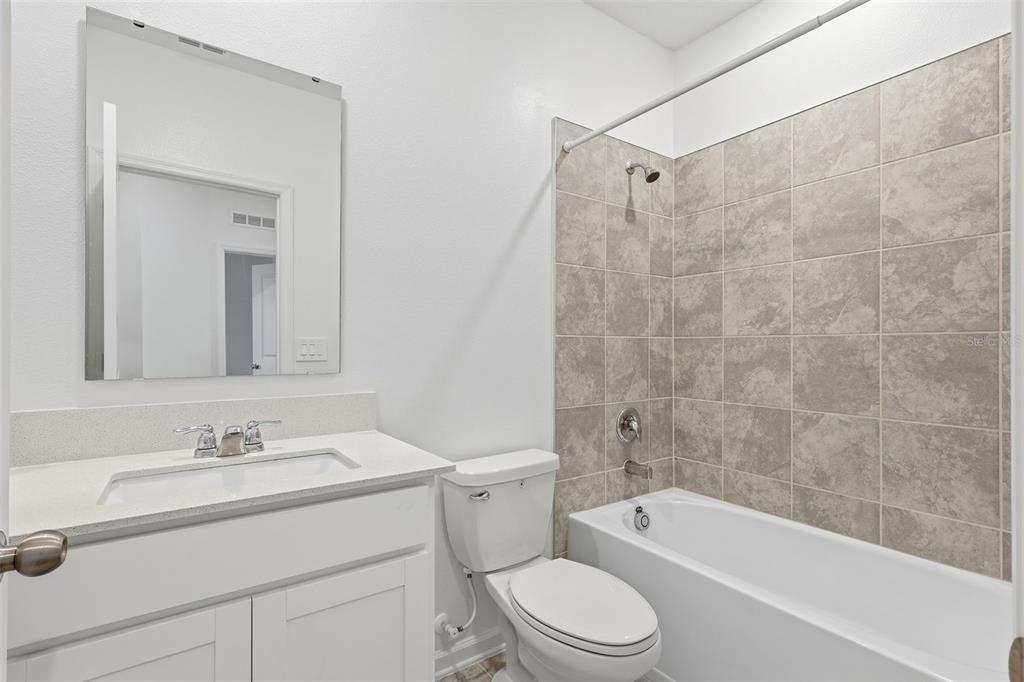 3303 Laurent Loop Davenport, FL 33837 - Photo 18 of 37 a bathroom with a granite countertop sink a toilet and shower