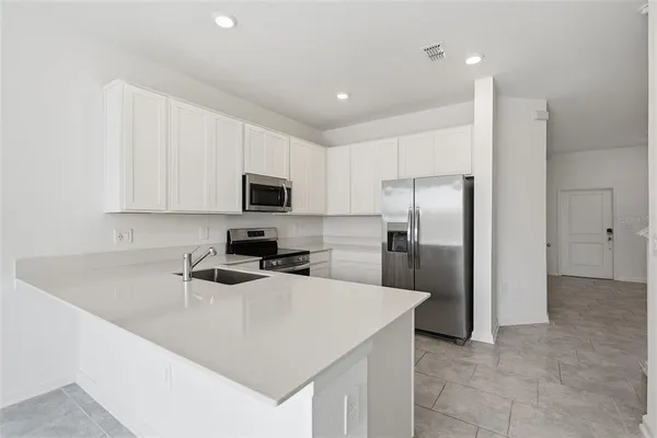 a kitchen with a refrigerator a microwave a sink and cabinets