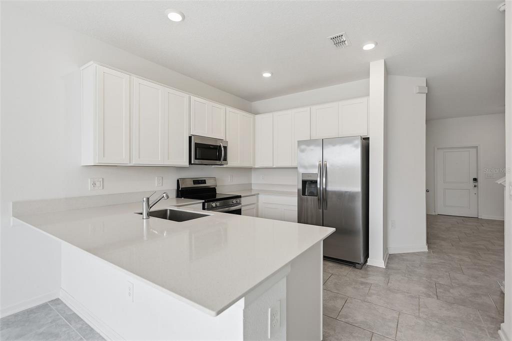 3303 Laurent Loop Davenport, FL 33837 - Photo 7 of 37 a kitchen with a refrigerator a microwave a sink and cabinets