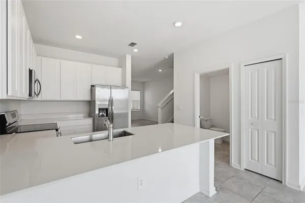 a kitchen with stainless steel appliances a sink a stove a refrigerator and cabinets